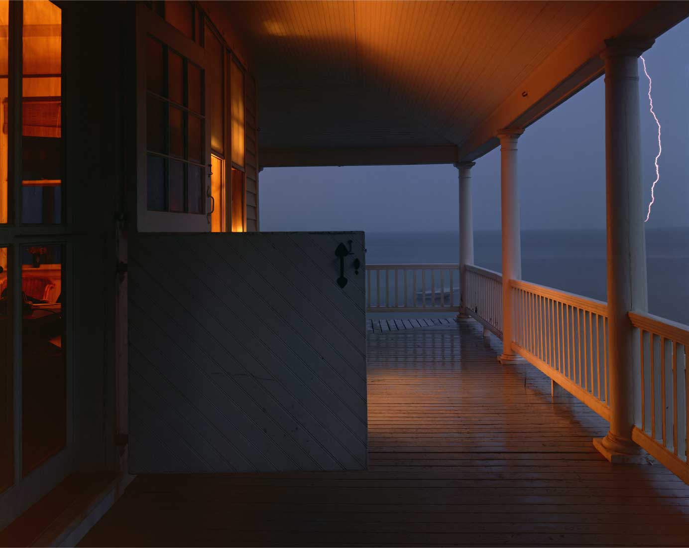 Photo of a porch at night during a lighting storm.
