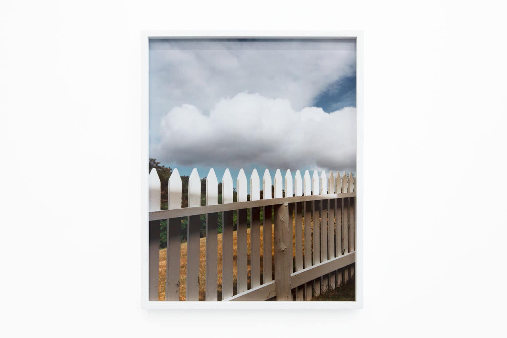 Photo of a white fence and a cloudy sky.