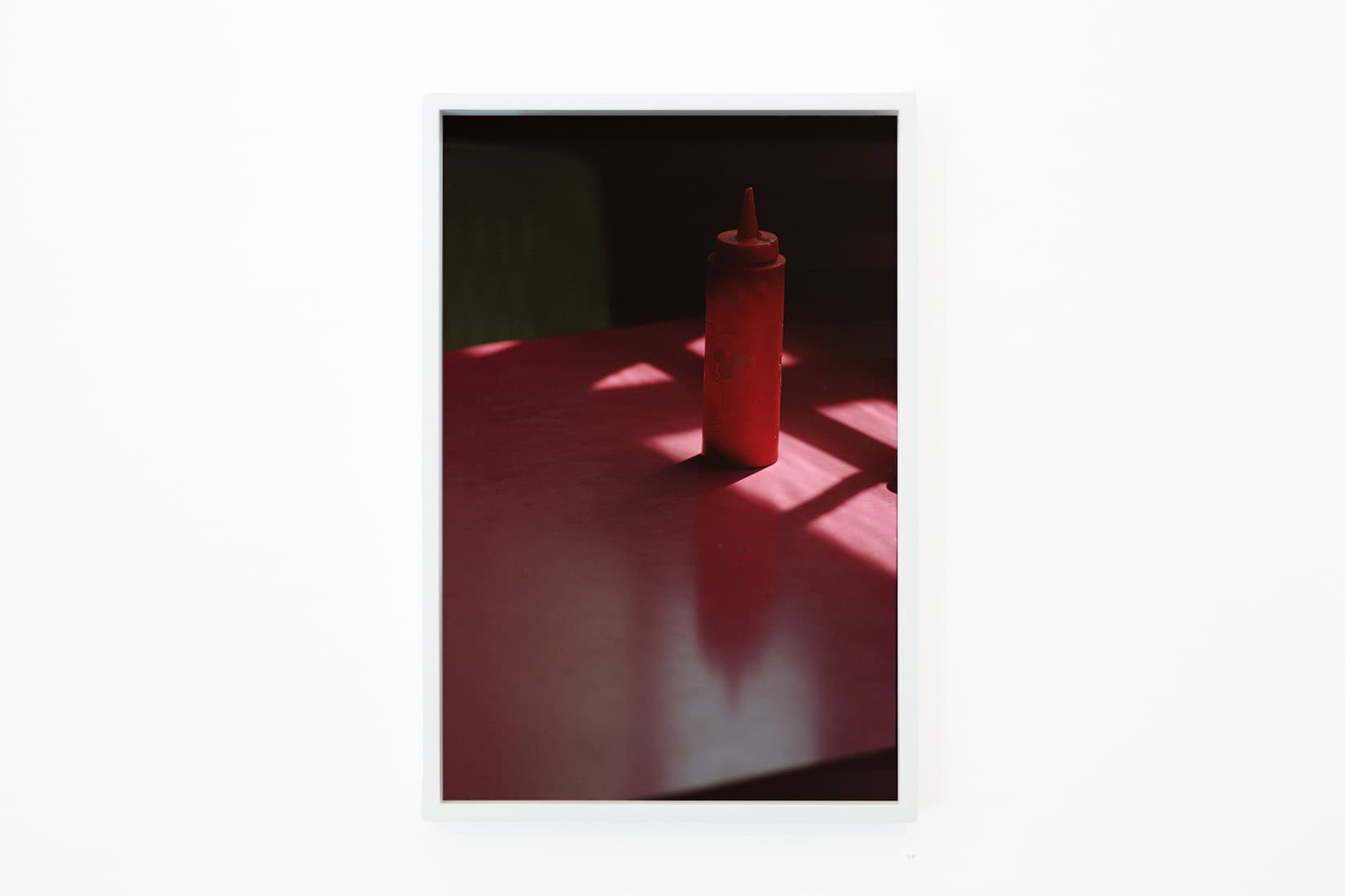 Photo of a red sauce bottle on a red table.