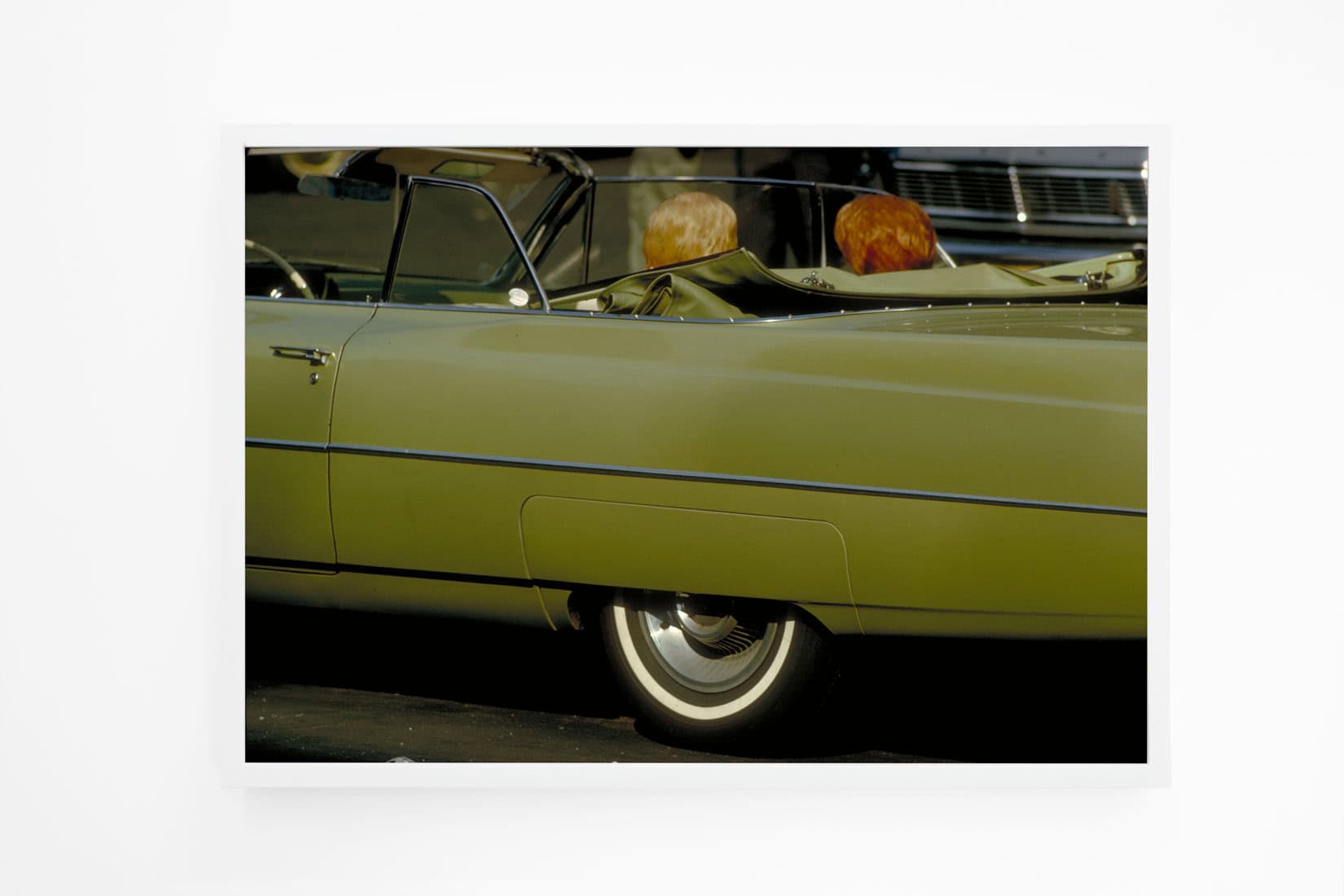 Photo of green car and the back two passengers heads.