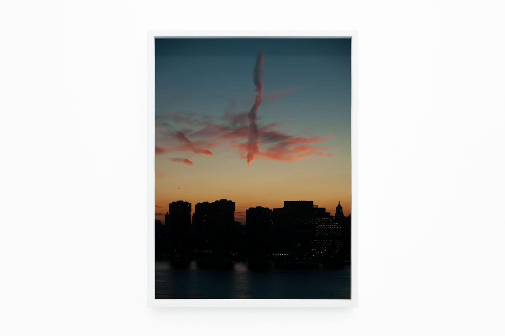 Photo of a pink cloud above a city at sunset.