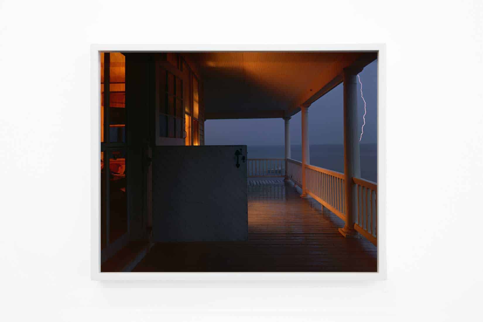 Photo of a porch at night during a lighting storm.