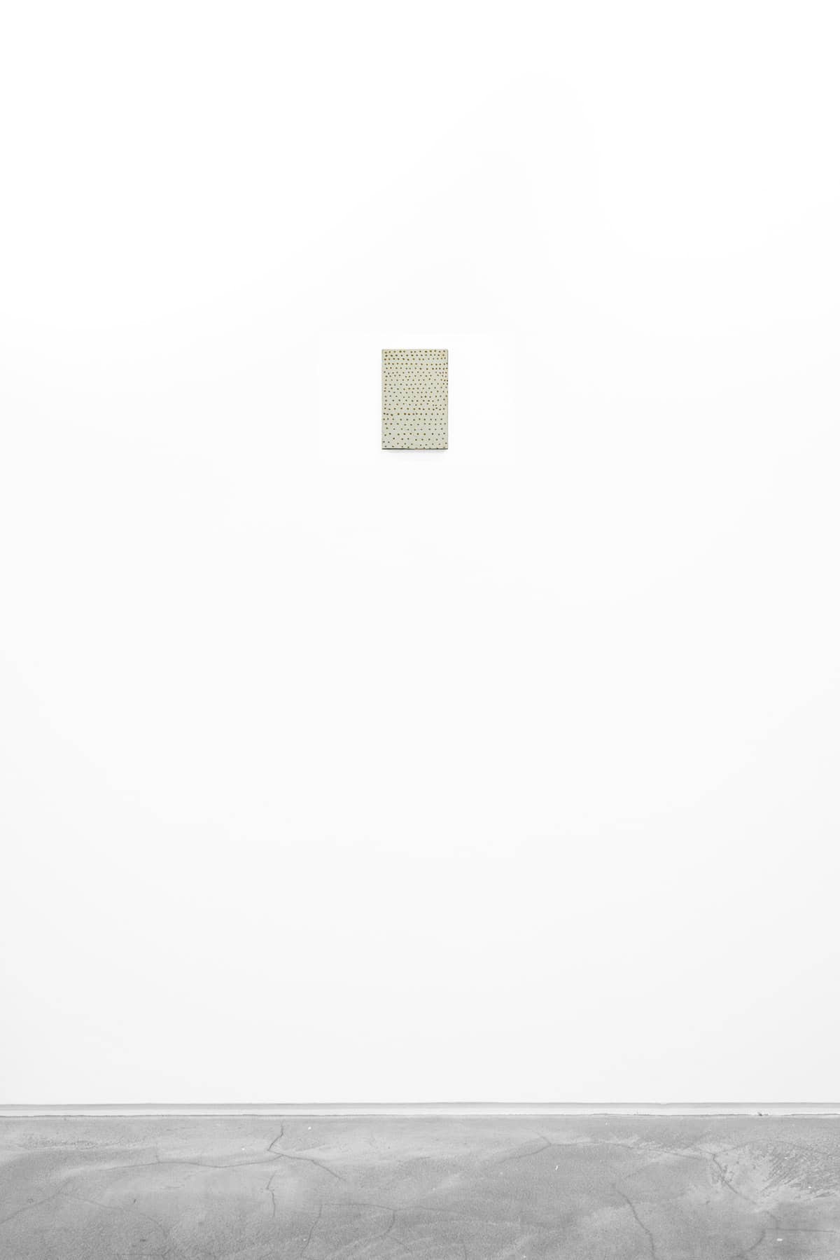 Abstract painting of green brown specks on cream paper and wood.
