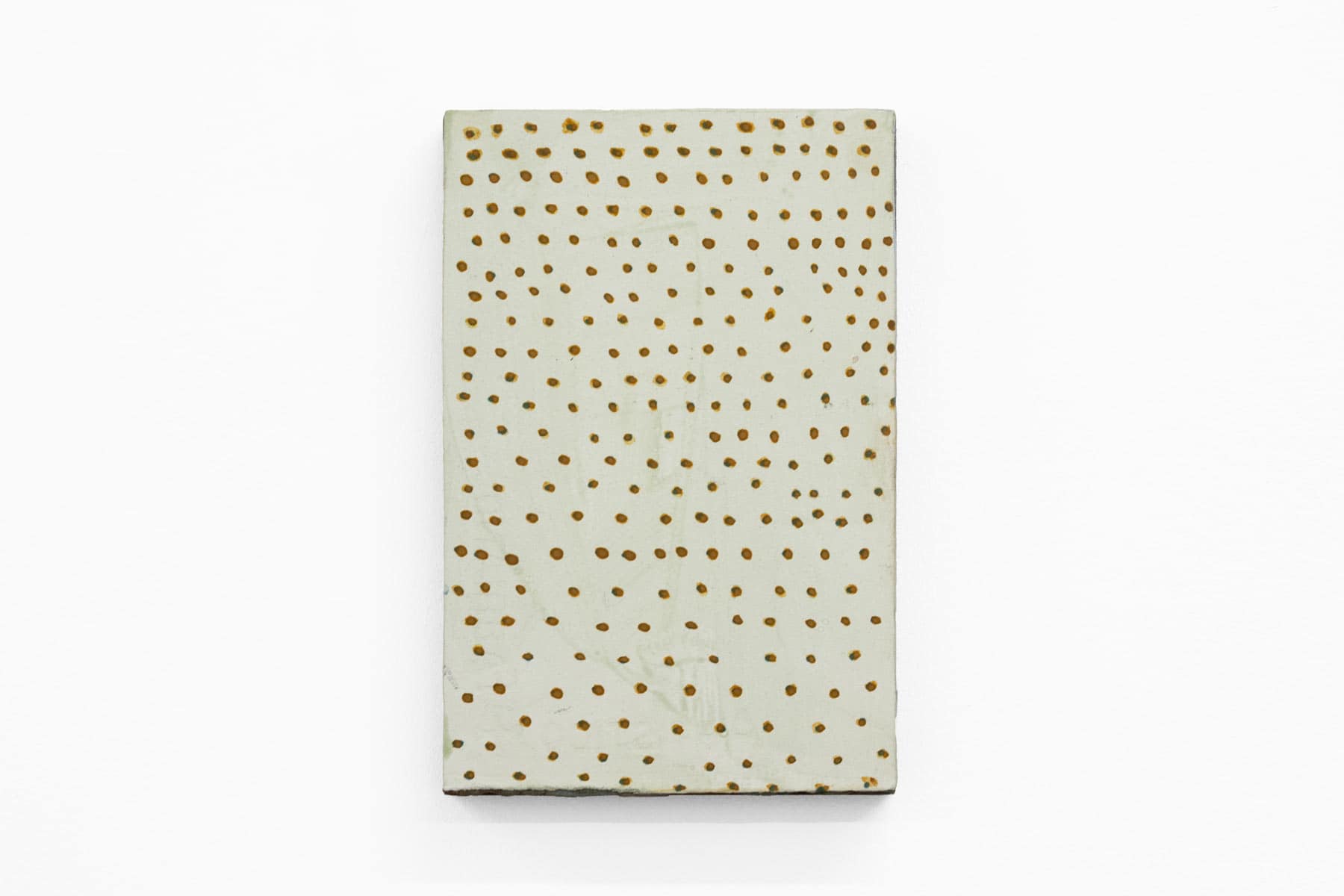 Abstract painting of green brown specks on cream paper and wood.
