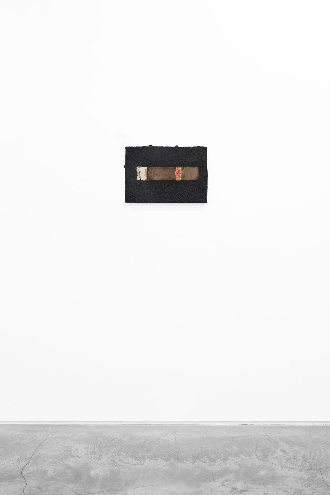 An artwork with a black background and a brown cigar in the center.