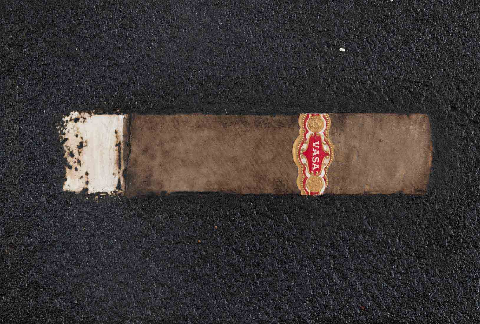 An artwork with a black background and a brown cigar in the center.