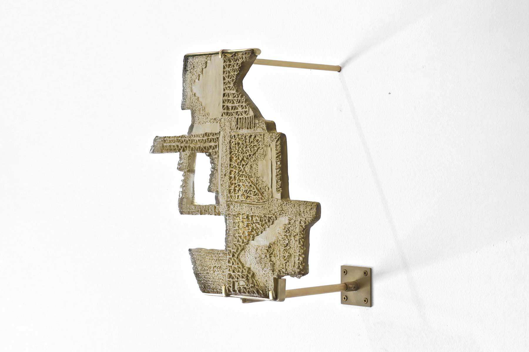 Sculpture made of cast glass attatched by rods to a wall.