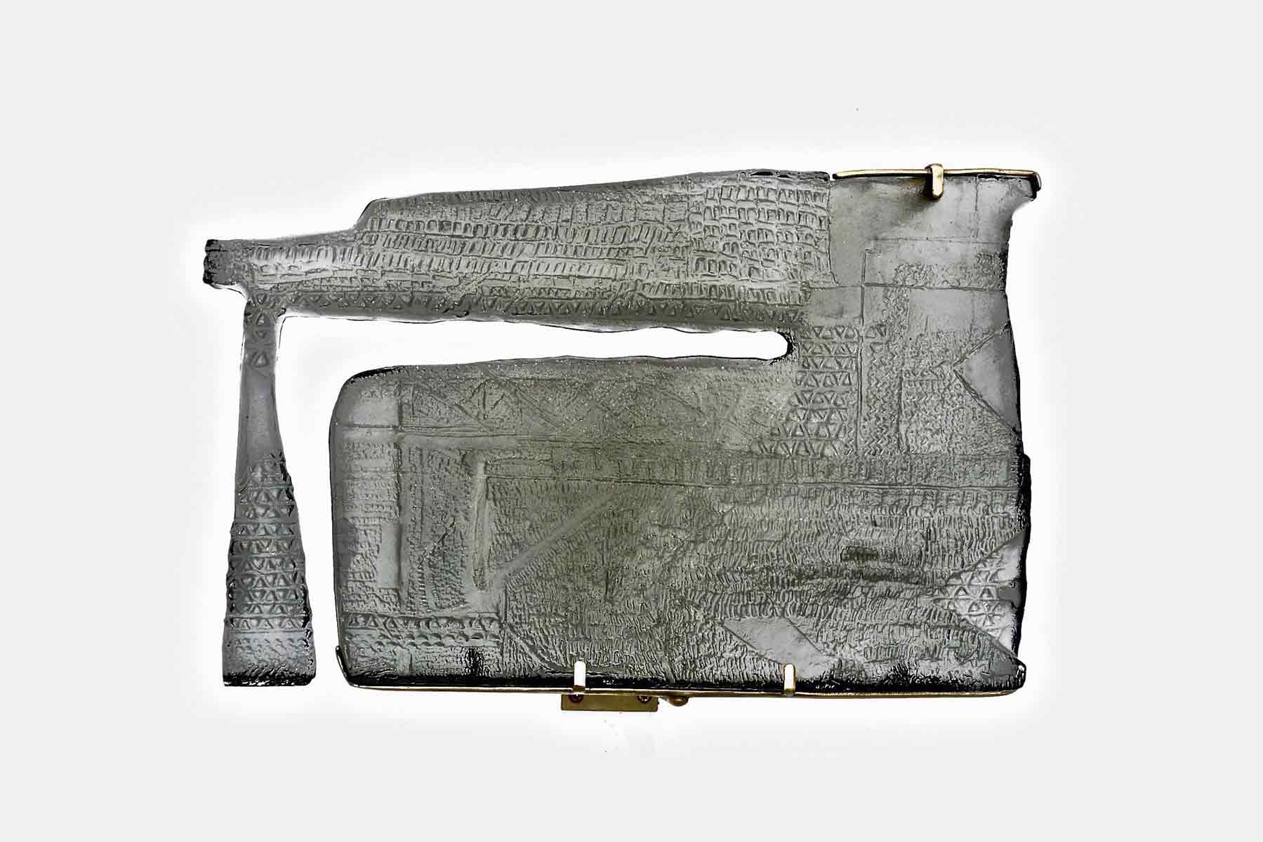 Sculpture made of grey cast glass attatched by rods to a wall.